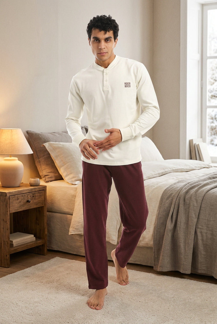 Man wearing a white long-sleeve shirt and burgundy pants on a white background